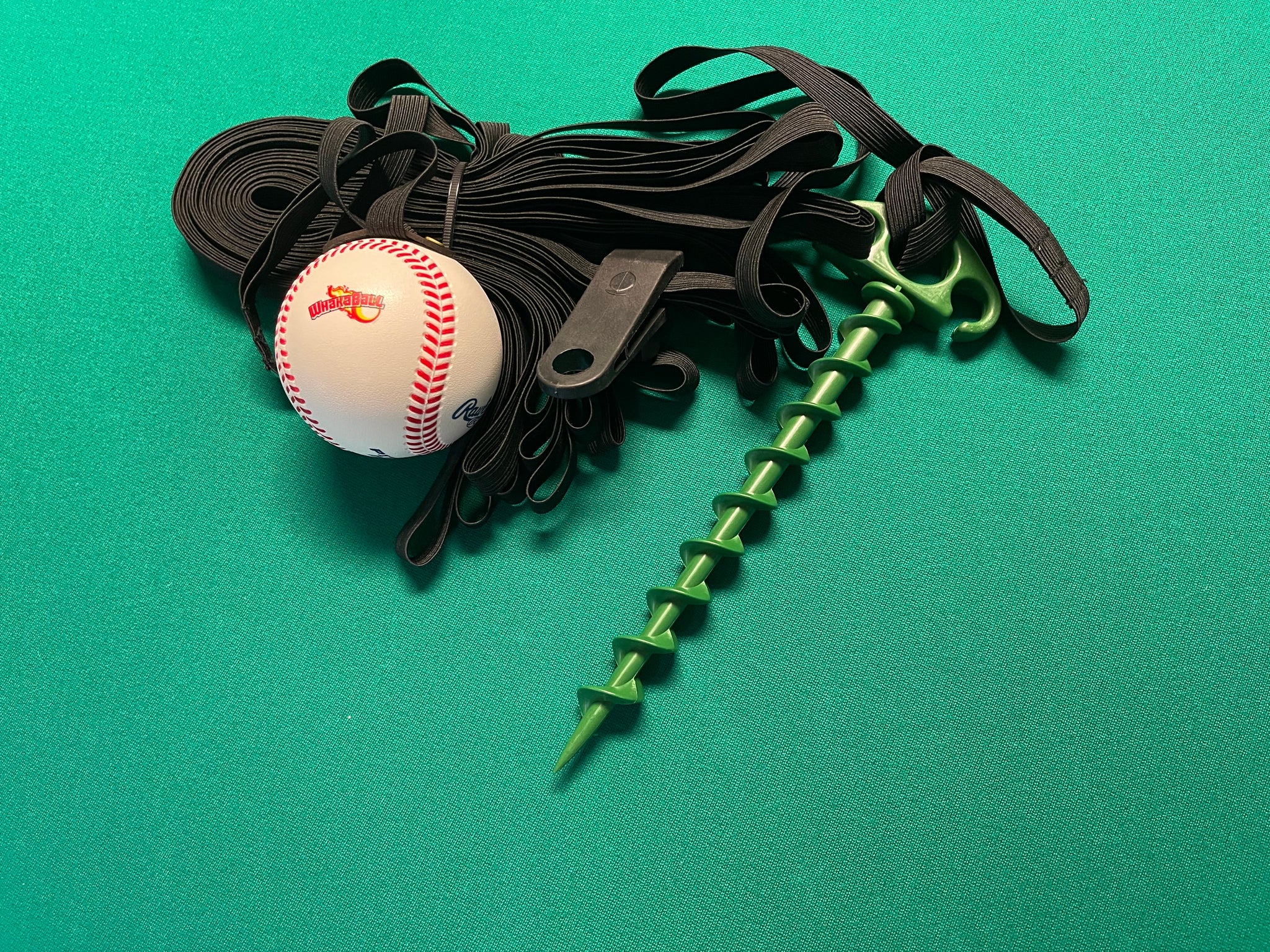 Baseball, green spike, and black strap on a green background